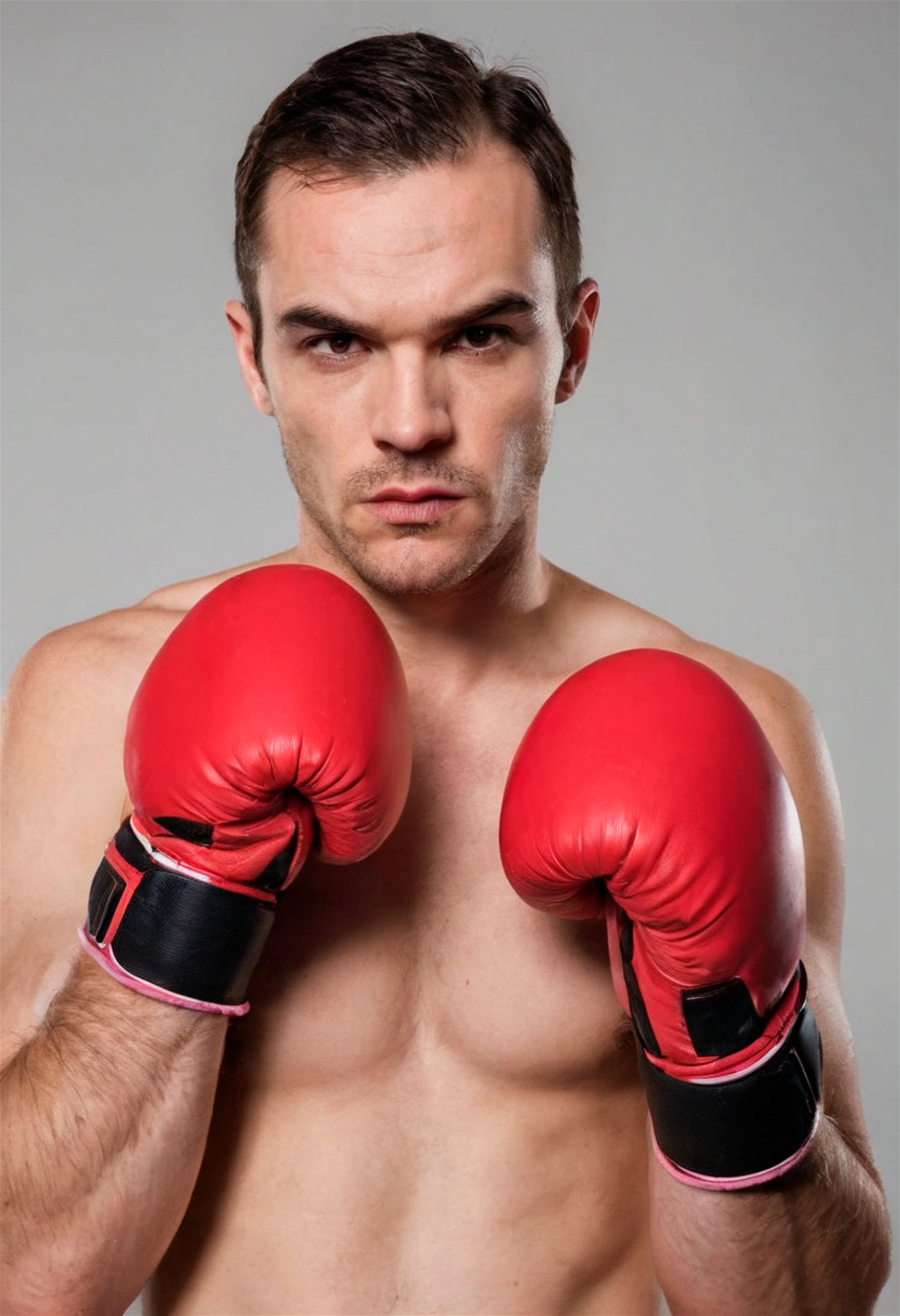 Close up portrait of male boxer, serious look, red gloves, dynamic pose